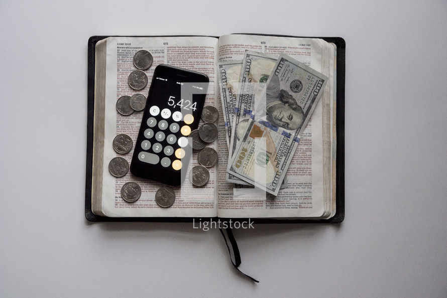 money, and calculator app on the pages of a Bible 