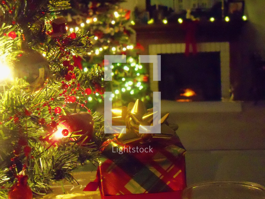 Wrapped Christmas present under the tree with fireplace in the background