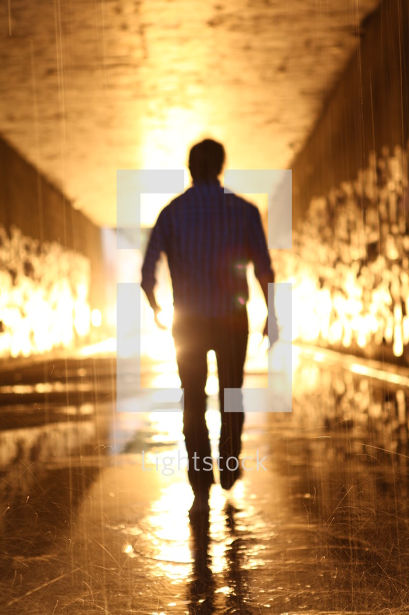 man walking through a glowing wet tunnel 