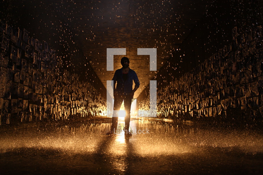 man standing in a glowing wet tunnel 