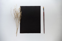 blank black paper with paint brush and twig 