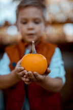 toddler boy holding a pumpkin 