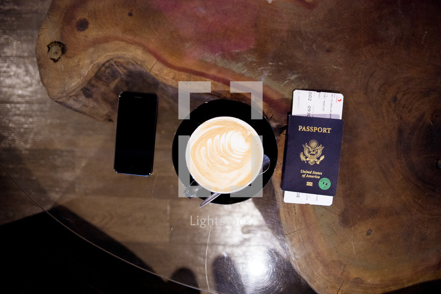 passport, plane ticket, cellphone, and coffee cup 