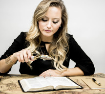 woman reading a Bible with a magnifying glass 