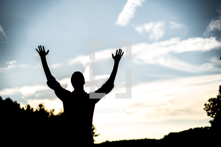 silhouette of a man with hands raised 