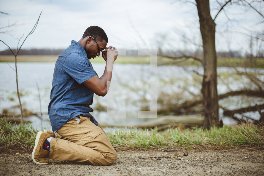 a man kneeling in prayer outdoors 