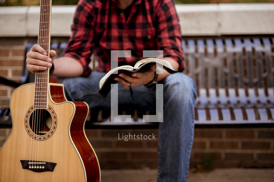 man with a guitar reading a Bible 