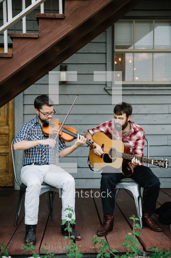 men playing a fiddle and guitar outdoors 