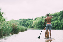 a man on a paddle board with his dog 