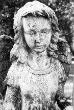 An old, weathered and historic statue of a female angel watching over a grave site as a reminder of Angels watching over us for all eternity. 