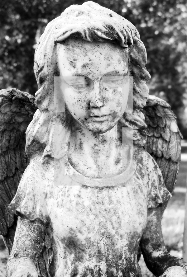 An old, weathered and historic statue of a female angel watching over a grave site as a reminder of Angels watching over us for all eternity. 