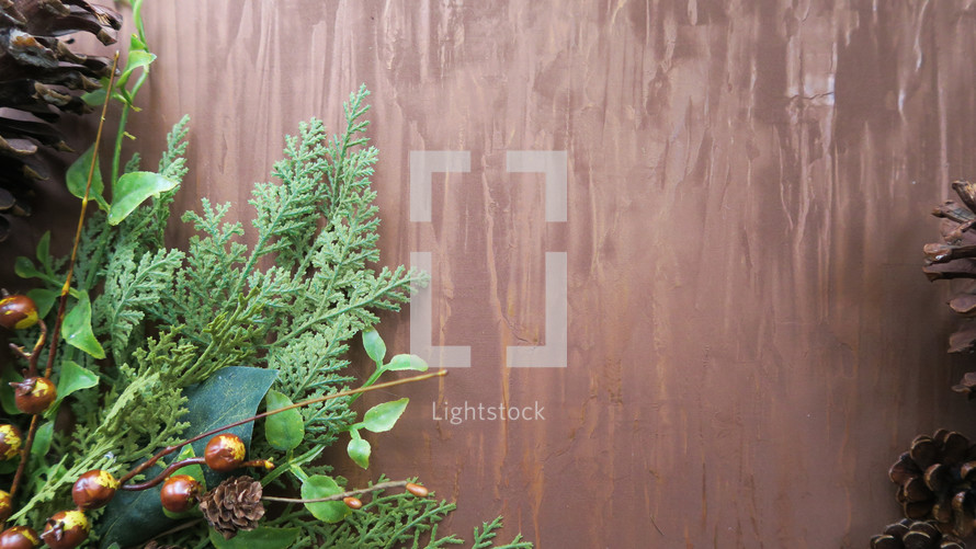 greenery swag and pine cones on a wood background 