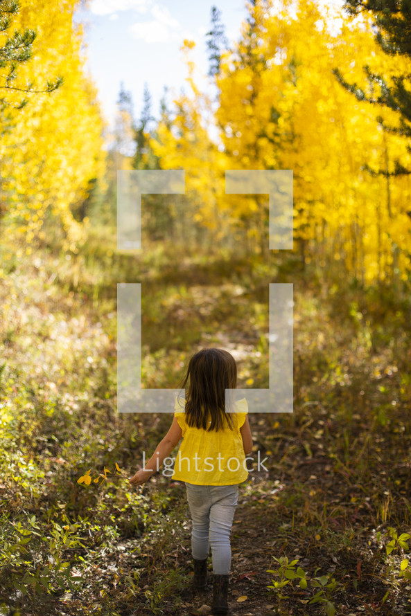 little girl walking under golden fall foliage 