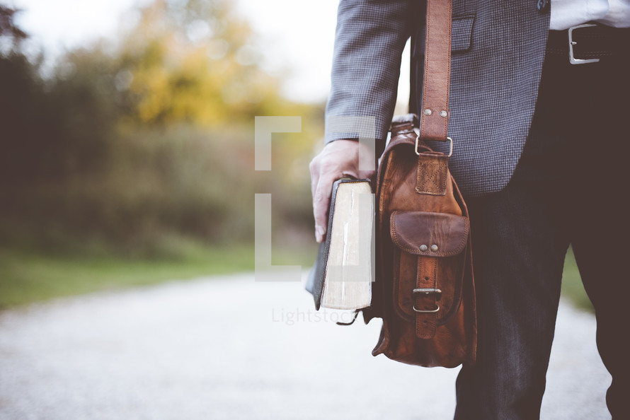 a man holding a Bible and satchel