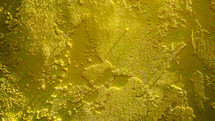 A yellow stucco wall showing texture and light reflecting in the textures of the wall. 