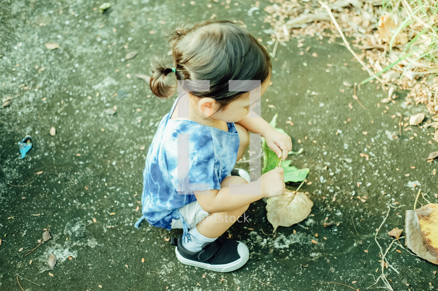 curious toddler picking up a leaf 