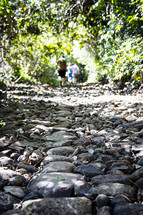 people walking down a rocky trail 