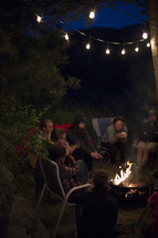 friends sitting around a fire pit at night 