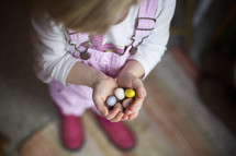 a child with cupped hands holding candy Easter eggs