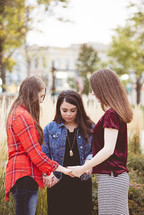 women holding hands in a prayer circle 