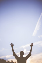 silhouette of a man with hands raised 