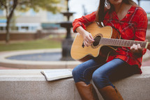woman playing a guitar and reading a Bible 