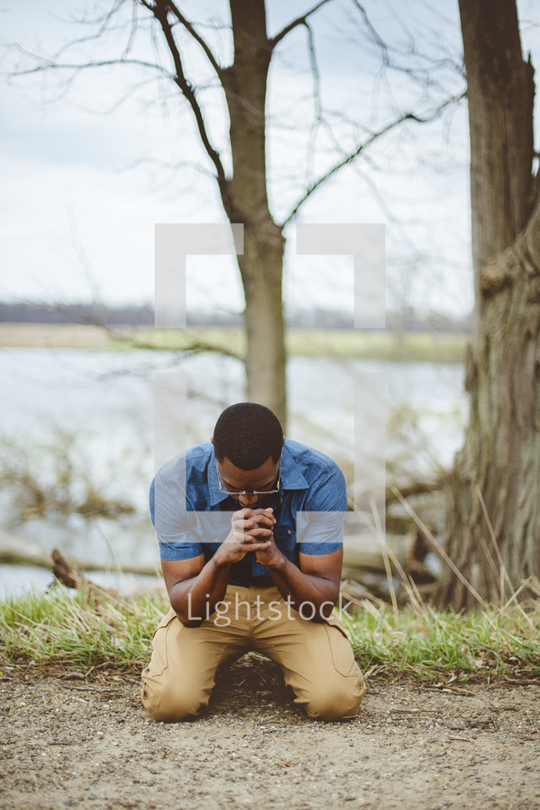 an African American man kneeling in prayer 