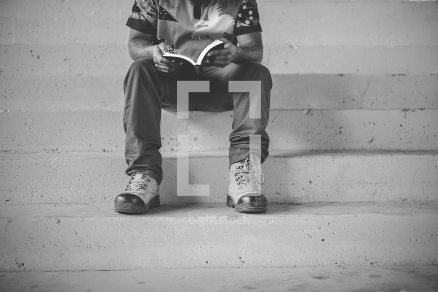 man sitting on steps reading a Bible 