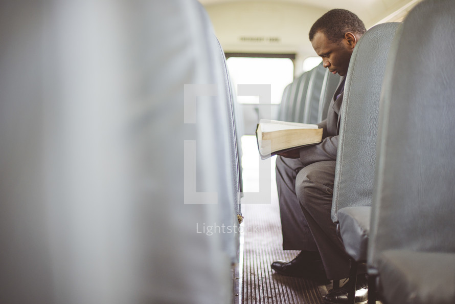 a man reading a Bible on a church bus 