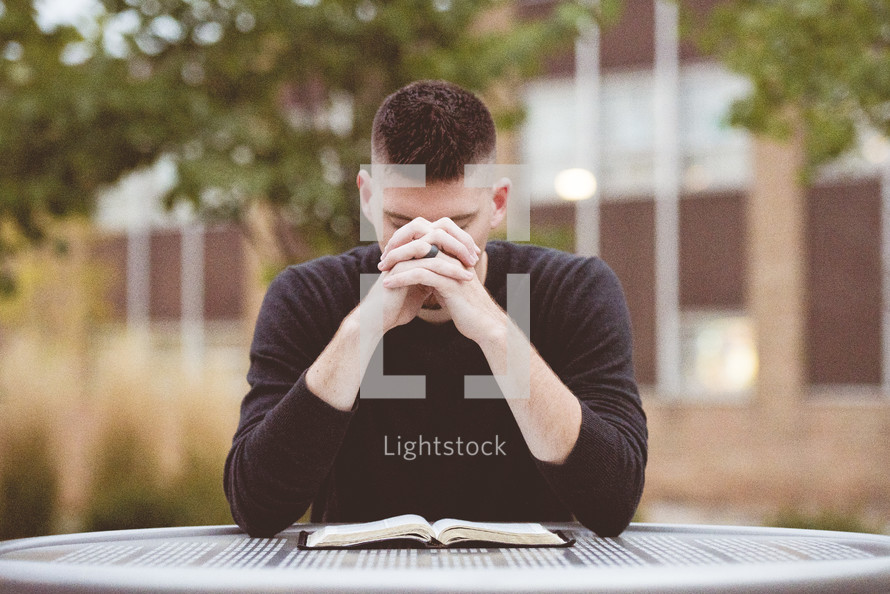 a man praying over an opened Bible 