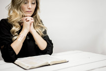 woman praying in front of an opened Bible 