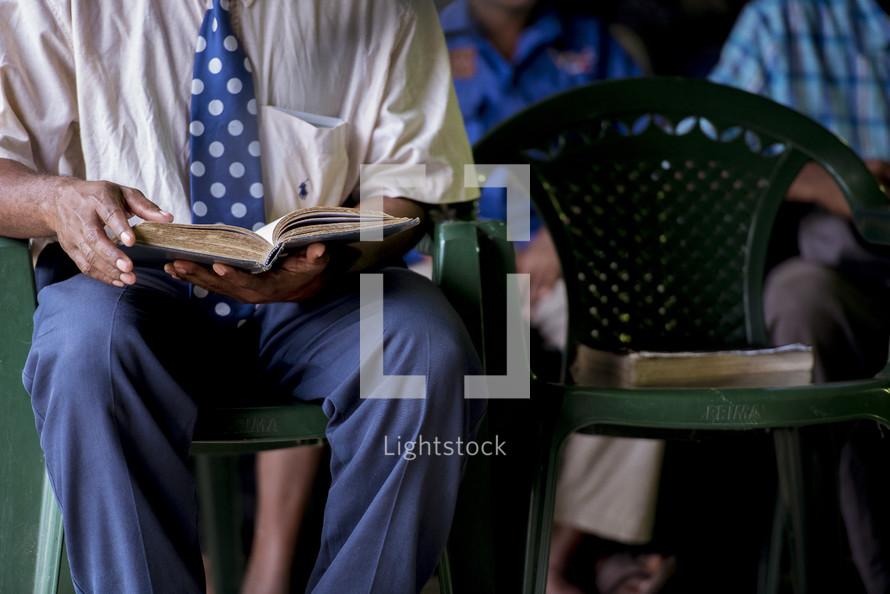 man reading a Bible during a worship service 