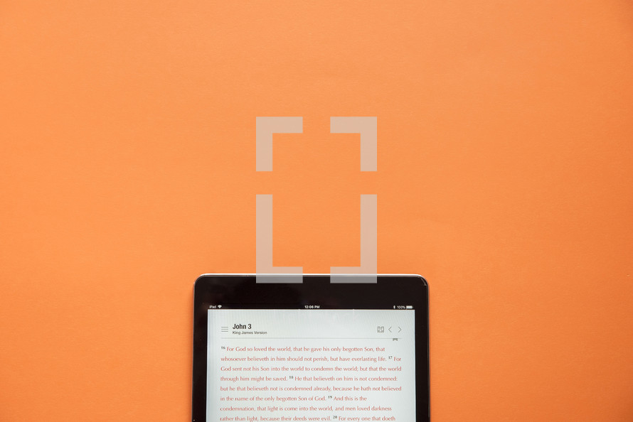 BIble on a tablet against an orange background 