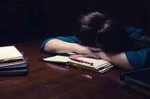 an exhausted woman with her head on her desk 