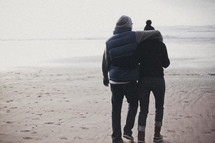 couple walking on a beach in winter coats