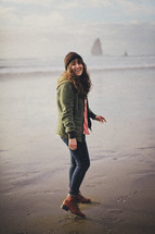 woman walking on a beach wearing boots 