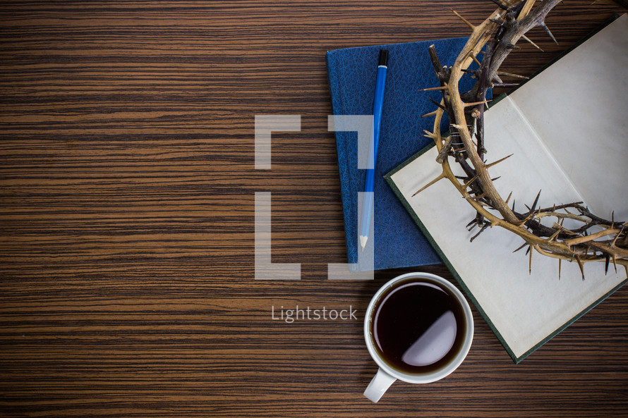 crown of thorns, journal, Bible, and coffee cup on a desk 