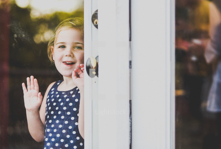 toddler girl looking out a glass door 