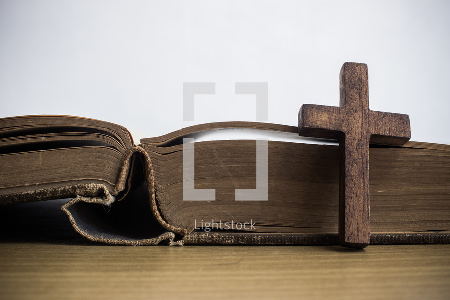 cross in front of the pages of a Bible 