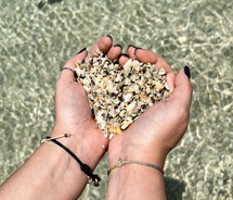 Hands in the shape of a heart with shells from Playa Conchal beach in Costa Rica.