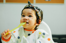 infant girl eating in a high chair 