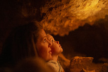 mother and daughter looking up standing in a cave 