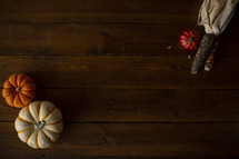 pumpkins and fall corn on a wood background 