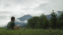 a man reading outdoors with a scenic view 