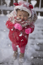 a toddler girl playing in snow but doesn't like it 