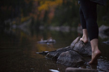 a woman standing on a lake shore barefoot in fall 