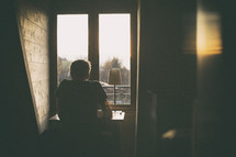 a man sitting at a desk in front of a window 