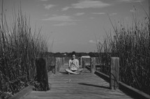 girl praying on a pier 