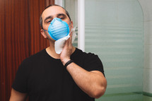man with medical mask wipes sweat on his face