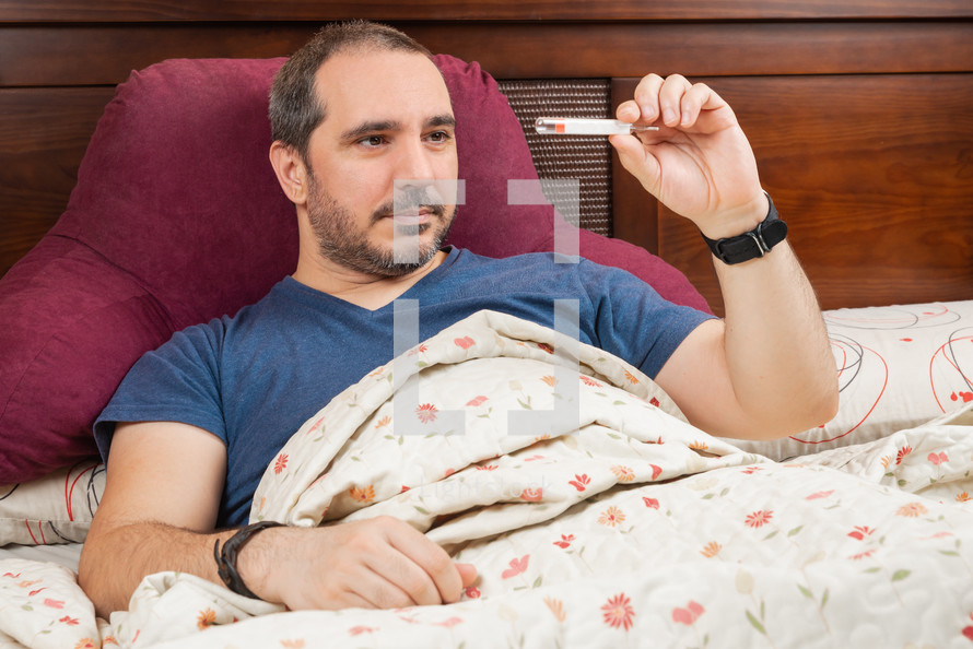 man in the bed with thermometer